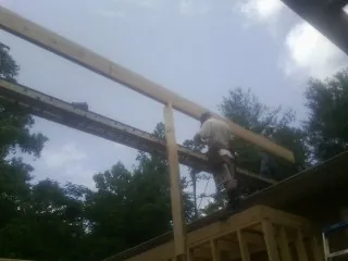 Carpenter setting a ridge beam over a new addition frame — Ice Dam Removal by Roofing Brothers in Lake Hamilton