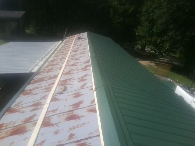Old rusted panels beside newly installed green metal roofing — Wind Damage Roof Repair by Roofing Brothers in Lake Hamilton
