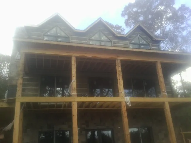 Dormers and porch framing on a large log home under construction — Roof Coating work by our crew in Lake Hamilton
