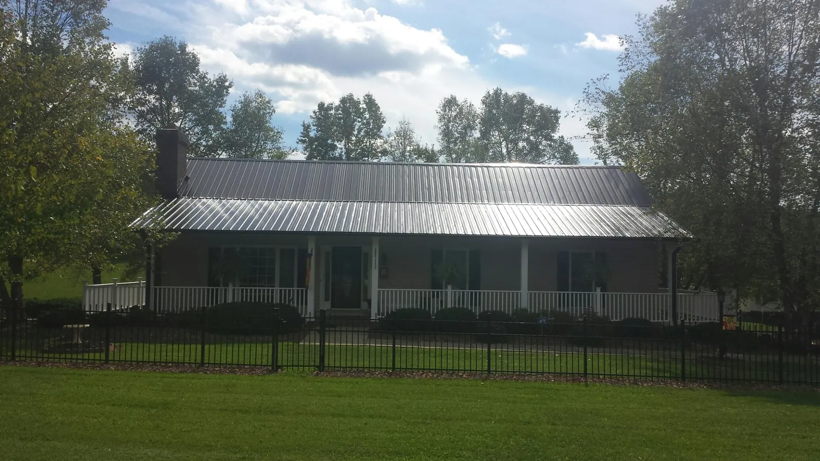 Gray metal roof on a brick ranch with a full width front porch in Lake Hamilton