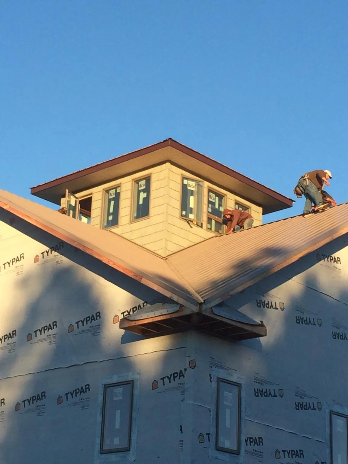 Roofers working around a rooftop cupola on a new metal roof at sunset — Roof Waterproofing in Lake Hamilton by Roofing Brothers